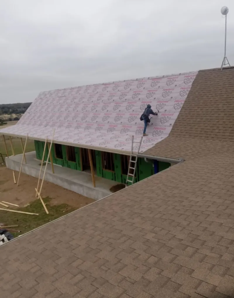 Worker preparing underlayment for a metal roof installation in Venus